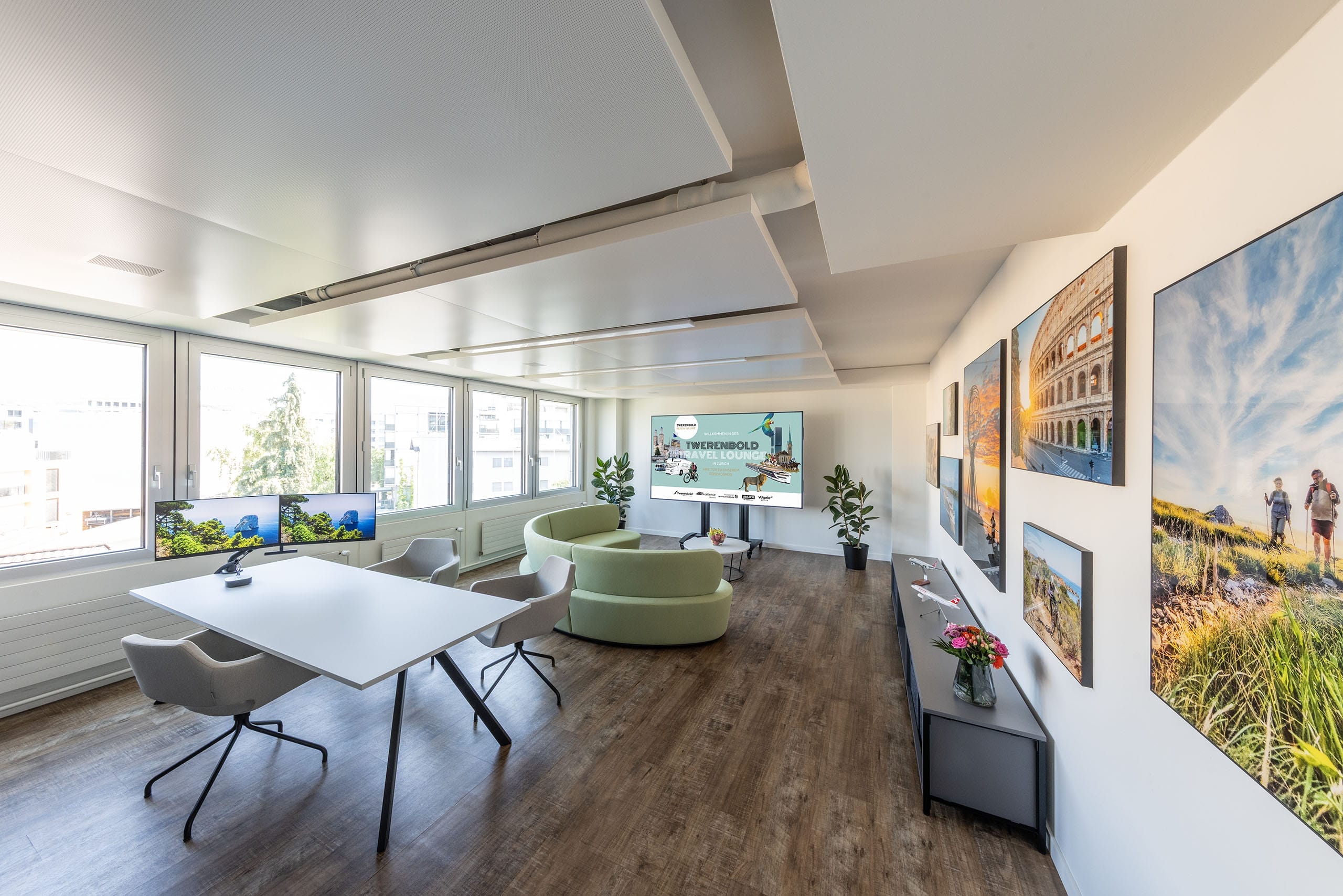 moderner, lichtdurchfluteter Büroraum mit Beratungstisch, Sofa und farbenprächtigen Bildern an der Wand